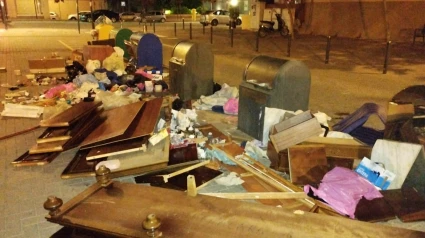 Basura y residuos de todo tipo esparcidos por la calle junto a una zona de contenedores en Lorca