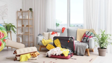 2XEA06F Interior of messy living room with sofa, scattered things and suitcases