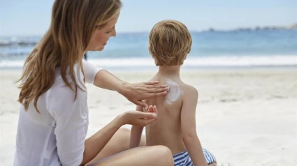 Madre poniendo crema a su hijo en la playa.