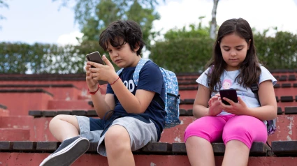Dos niños juegan con el móvil en el recreo