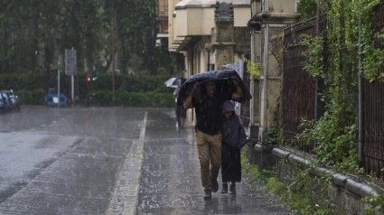 Dos personas se refugian de la lluvia y el granizo caído el viernes en Vitoria por el paso de la DANA por el norte del país
