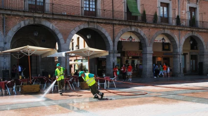 Dos barrenderos refrescan el suelo ante el calor de julio