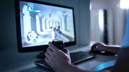 Persona jugando a un videojuego mientras sujeta una bebida energética