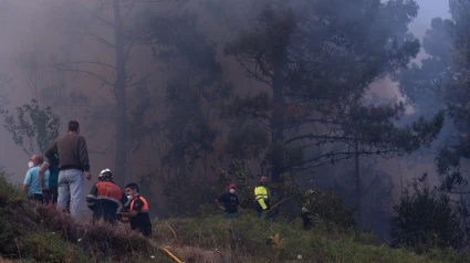 Varias personas tratan de extinguir el fuego, a 5 de agosto de 2025, en Ponteceso, A Coruña, Galicia (España).
