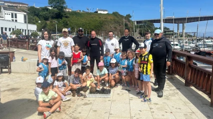 Submarinistas y niños posan junto a los objetos recuperados del fondo del mar