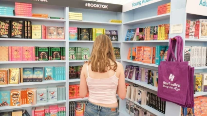 2X9AHAT 2X9AHAT Hay Festival, Hay on Wye, Powys, Wales, UK  Thursday 30th May 2024  Young woman browses the Young Adults ( YA ) and Booktok selection of new books in the Hay Festival bookshop - Photo Steven May / Alamy Live News