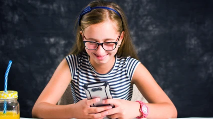 T4GYGC Happy teen girl looking at her phone and smiling