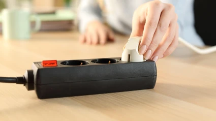 Una mujer enchufando un cable a un alargador en su casa