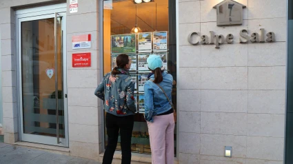 La gente mira los escaparates de las ofertas de las agencias inmobiliarias en la ciudad de Calpe (también conocida como Calp) en la provincia de Alicante.