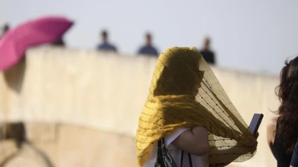 Una turista se cubre la cabeza con un pañuelo mientras camina por el Puente Romano de Córdoba