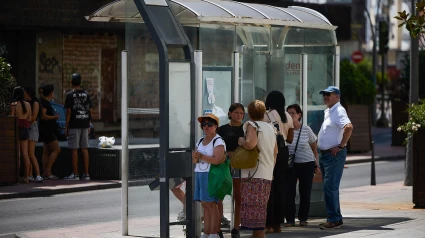 Unas personas esperan a un autobús a la sombra de una parada en una terraza de la localidad toledana de Talavera de la Reina
