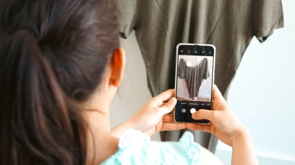 Una joven toma fotografías de su ropa usada para venderla en línea.