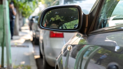 Espejo retrovisor de un automóvil estacionado cerca de la acera al costado de la calle