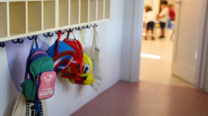 Varias mochilas en una percha de un aula de 0 a 3 años