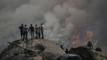 Varias personas observan el incendio forestal declarado ayer en Avión (Ourense)