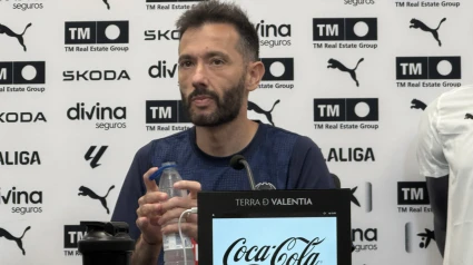Carlos Corberán ha comparecido ante los medios en la Ciudad Deportiva de Paterna en la previa del partidazo del domingo en el Estadio Johan Cruyff ante el FC Barcelona. El técnico ha esquivado la polémica de la designación del estadio que ha sido actualidad durante los últimos días. Valora positivamente el mercado de fichajes y tampoco ha querido mojarse con el objetivo para la temporada. No deshoja la margarita respecto a un posible cambio de sistema ante los de Flick y asegura que no hay pesadillas respecto al 12-1 que los culés infringieron en dos partidos consecutivos, Liga y Copa, la temporada pasada a los valenicianistas con el de Cheste ya en el banquillo ché. ¿Qué opina de la circunstancia de jugar en el Johan Cruyff y que se comunique solo con 5 días de antelación?Lo primero es que está la RFEF y LALIGA son los que fijan unas normas. Ellos tienen que velar por que las normas que ellos fijan se cumplan. No nosotros. Es una situación atípica, no es normal. Lo que yo he hecho es centrarnos en lo que depende de nosotros: nosotros mismos y el rival, independientemente del campo en el que se juegue. No es normal esta situación y afecta al aficionado, lo más importante del fútbol. Cuando se supo el estadio, el Club hizo un esfuerzo en movilizarse para asegurar que 290 valencianistas podrían estar junto al equipo y eso es positivo, para nosotros es necesario. Quien fija las normas tiene que velar por ellas. Es una situación atípica y no es normal ni acorde al nivel de prestigio que debe tener esta competición.Tras los dos resultados negativos de la temporada pasada ante el FC Barcelona, ¿cómo se afronta el partido?Se afronta sabiendo que jugamos contra uno de los mejores equipos del mundo y eso te pone en la tesitura de saber la exigencia que tiene este partido. Cuando juegas contra el FC Barcelona tu concentración tiene que ser máxima y tu capacidad de respuesta también. Si tu respuesta no es acorde a las velocidades a las que juegan, vas a sufrir. Tiene que ser máxima porque jugamos contra uno de los mejores equipos del mundo.Tras el 7-1 les puso el vídeo a los jugadores. ¿Lo ha vuelto a hacer esta semana? ¿Ha estado muy presente aquel partido en la preparación de este?El 7-1 y el 0-5 son dos de los días más complicados que he vivido como entrenador del VCF. Después de los duros golpes que recibimos, me gustó que el equipo fue capaz de levantarse ante el RC Celta de Vigo en un partido importantísimo y ante el CD Leganés, ganando en Mestalla 2-0, lo que nos permitió seguir escalando para conseguir el objetivo. Me quedo con la entereza que tuvo el equipo para levantarse. Como en cada partido miramos las fortalezas y debilidades del rival, lo afrontamos con la entereza y la motivación necesaria.¿Cómo están Diakhaby y André Almeida?Diakhaby tuvo dos partidos con la selección que le han venido muy bien para coger el ritmo competitivo y Almeida ha entrenado con normalidad. Todos los efectivos están disponibles para el partido.¿Es una falta de respeto decir que le beneficia jugar en un campo más pequeño?Escucho poco lo que se dice, lo de hablar de un campo más pequeño es erróneo porque son las mismas que el Spotify Camp Nou (105x68) y estamos preparados y trabajando para lo importante. Los Ferran, Raphinha, Rashford, Lamine Yamal… eso está por encima de las dimensiones del campo. Estamos centrados en encontrar nuestra mejor respuesta, que es lo que nos hará ser un equipo competitivo.¿Es un reto especial este partido ante el FC Barcelona?Cada partido es un reto, queremos defender de la mejor forma posible la camiseta y trabajamos para eso.¿Cuánto le influyen los partidos del año pasado y cómo puede afectar a los jugadores?Sencillo, con ganas de competir mejor el partido de lo que lo hicimos la temporada pasada. Estamos con muchas ganas de competir de la mejor forma. El FC Barcelona es un equipo con grandes jugadores y debemos prepararnos para cualquier situación que pueda darse durante el partido.¿Puede cambiar el sistema táctico? Trabajamos con línea de 4 y de 5, para mí lo importante no es el sistema sino la concentración y la capacidad de respuesta que tengas ante lo que vaya a suceder en el partido.¿Cómo está Thierry?Si mañana termina el entrenamiento estará listo para el partido, esto es muy positivo para el VCF. Si entro en detalle en su recuperación, es un ejemplo para todos, donde todos nos debemos de mirar porque ha sido capaz de superarse ante la adversidad. Su espíritu y su compromiso es ejemplar para todos.¿Qué cambios de actitud y tácticos hay que llevar a cabo para que no suceda lo mismo?El año pasado jugamos con una línea de cuatro en defensa, luego cambiamos a 5 y el de Copa empezamos con la de 5. El resultado no fue bueno y eso dice que no se juega bien en función del sistema, hay cosas superiores al sistema. Eso tiene que ver con la concentración constante. El FC Barcelona antes sometía a través de pases horizontales y circulaciones, ahora con Flick tratan de dañarte en vertical, eso lo han instaurado al igual que reducir el espacio de ataque. Los partidos se juegan prácticamente en tu campo. Son aspectos que tienen que ver con el partido por encima de cualquier sistema. Hay que analizar su fase defensiva y ofensiva para ver qué respuesta requiere para competir el partido en mejores condiciones que la otra vez.Es la primera rueda de prensa post mercado. Ahora que tiene la plantilla cerrada… ¿Es capaz de fijar un objetivo? ¿Se puede pelear por una posición europea?Mi objetivo nunca ha cambiado: hacer el VCF más competitivo posible y ser lo más competitivos posibles en cada partido para darle la mayor de las ilusiones a la afición. Y preparar el siguiente partido. Y cuando no lo consigamos, responsabilizarse, levantarse y seguir trabajando para darle a la afición el orgullo y el sentido de pertenencia que queremos que tengan. La clasificación es una consecuencia, lo importante es la preparación y el foco en cada partido.¿Hasta dónde le puede influir lo de la línea adelantada del FC Barcelona? ¿Le cambia algo en su forma de jugar?Todas las formas de jugar de un rival condicionan la manera de preparar el partido. Más que condiciona, genera un tipo de partido. Cada equipo llevamos a cabo una propuesta de juego y eso condiciona el juego.¿Cómo condiciona esta situación de jugar en el Johan Cruyff?El rival no ha cambiado, es el FC Barcelona. La preparación la hemos hecho con absoluta normalidad focalizados en nosotros y en el rival que vamos a enfrentar.¿Tienes mejor ataque que el año pasado?La plantilla es diferente a la del año pasado. Hemos tenido 13 salidas y 10 jugadores que han llegado. Es una plantilla diferente. El año pasado tuvimos un buen rendimiento y eso nos permitió conseguir un buen objetivo. Este año debemos exigirnos nuestra mejor versión para defender de la mejor forma posible nuestro escudo.¿Es injusta esta situación con el Johan Cruyff?Para mí es atípica porque el estadio normalmente se sabe con anterioridad. Hay dos organismos que fijan unas normas y deben velar por que se cumplen. Está en ellos que se cumpla, no en nosotros. En mí está trabajar el partido y competir de la mejor manera.¿Tiene una espina clavada con el FC Barcelona?Son dos partidos dolorosos, a nadie le gusta perder y menos de esa manera. En su momento generó dolor y tratamos de transformarlo en rabia y motivación para demostrar que eso no representa a esta institución.Valoración del mercado de fichajes.Mi valoración es positiva. Estoy satisfecho acorde a las posibilidades que el Club tenía, se ha hecho un mercado bueno en este sentido.¿Qué le aporta Thierry?Muchas cosas. Desde ser un ejemplo en cómo ha manejado su recuperación, en no rendirse ante las dificultades, y eso es muy importante para los compañeros. Lo siguiente, es un lateral derecho con unas capacidades físicas por encima de la media, con un nivel de explosividad y velocidad muy grande y va a ser un jugador muy importante, sin duda.Dijo Diego López que igual que se ganó en el Bernabéu se puede ganar al FC Barcelona. Hay dos aspectos emocionales que influyen mucho en el rendimiento: la confianza y la exigencia. Que los dos estén en el máximo nivel ayuda para que el equipo rinda bien. Deben estar equilibrados o que haya un poco más de exigencia. Que el jugador llegue con niveles elevados es positivo.¿Cómo trabajas con los delanteros, que tienen perfiles distintos a la temporada pasada?Si comparas Sadiq, Rafa Mir y Hugo Duro con Danjuma, Hugo y Lucas, son diferentes. Estoy de acuerdo. Queremos el máximo rendimiento de cada uno en virtud de lo que es capaz de hacer y adaptar el juego a sus capacidades.¿Jesús Vázquez tiene alguna posibilidad de jugar?Siempre tienen posibilidades de jugar, Jesús y el resto de jugadores. Ha tenido momentos buenos, buenos partidos y un buen rendimiento. Es muy importante.Carlos Corberán en Paterna