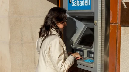 Una joven saca dinero de un cajero automático del Banco Sabadell en España