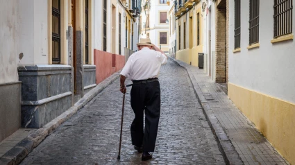 Jubilado con bastón caminando por una calle adoquinada en Sevilla, Andalucía, España.