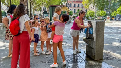 Familia joven con niños bebiendo agua en un día caluroso, ciudad con ola de calor, en una escena callejera en Sevilla
