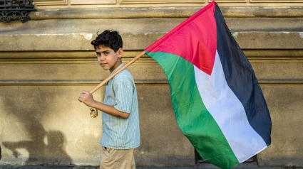 Un niño marcha sosteniendo la bandera palestina.