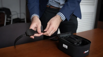 Una persona muestra una pulsera electrónica de geolocalización telemática