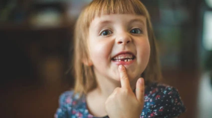 Una niña muestra sus dientes de leche