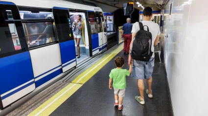 Un padre caminando por el andén del metro de Madrid con su hijo