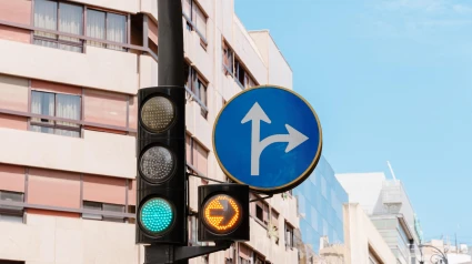 Vista de calle urbana con semáforo verde y señal azul que muestra solo giros hacia adelante y hacia la derecha