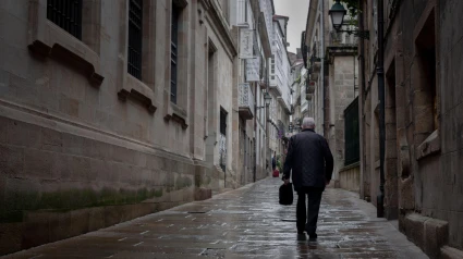 Un anciano solitario camina por una calle del casco antiguo de Santiago de Compostela