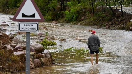 Un hombre cruza un badén inundable durante el que el aviso rojo (riesgo extremo) por precipitaciones que pueden acumular 180 litros por metro cuadrado en doce horas estará activo hasta la medianoche de hoy en el litoral de la provincia de Valencia