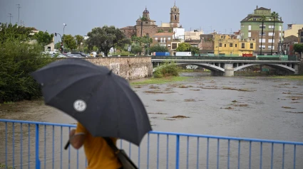 Una persona cruza un puente sobre el río Ana en Burriana durante el que el aviso rojo (riesgo extremo) por precipitaciones que pueden acumular 180 litros por metro cuadrado en doce horas estará activo hasta la medianoche de hoy en el litoral de la provincia de Valencia