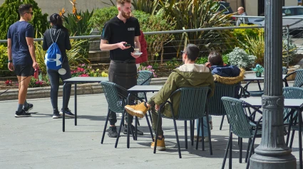 Un camarero sirve a una joven pareja que está disfrutando en un café al aire libre en Tarragona