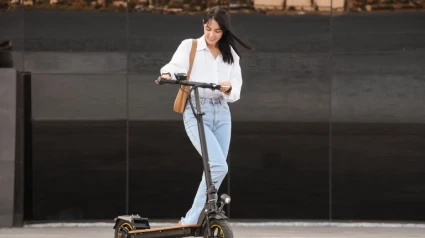 Joven empresaria montando patinete eléctrico al aire libre