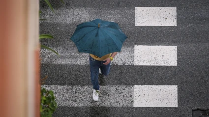 Un hombre se protege de la lluvia en La Foia, en Elche