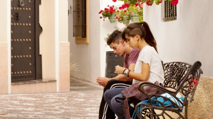 Una pareja de adolescentes enviando mensajes de texto en sus teléfonos móviles, Estepona, Andalucía.
