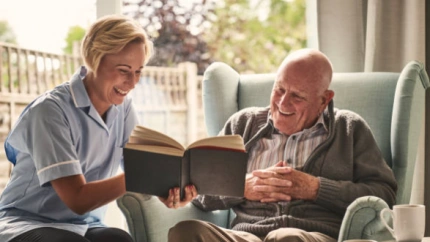 Una persona leyendo un libro junto a la persona que cuida