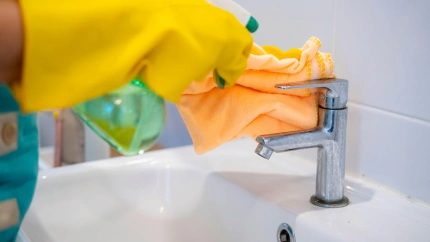 Empleada del hogar limpiando el grifo de un baño