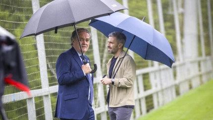 El presidente de la Real Sociedad, Jokin Aperribay (i), y director de fútbol del club, Erik Bretos, se protegen de la lluvia durante una sesión de entrenamiento en Zubieta.