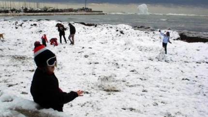 Niños jugando a la orilla del mar con la nieve que hizo acto de presencia en enero de 2017