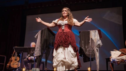 Mature woman Performer singing on the stage. She is dressed in period costume. Stage interior of Theatre during performance at night