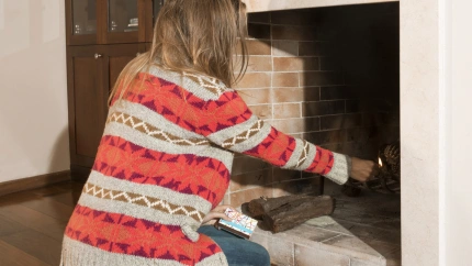 Una mujer enciende la chimenea de su casa en un día de inverno