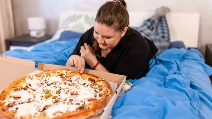 Una chica come una pizza en la cama
