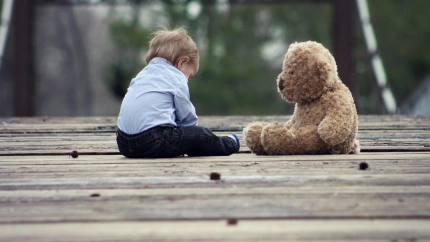 Un niño, junto a un peluche