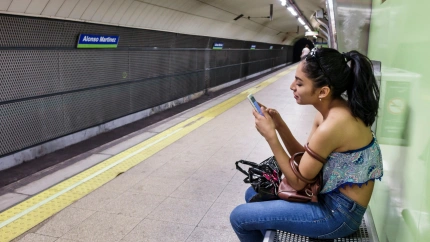 Una joven espera el metro mirando su móvil en Madrid