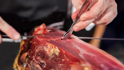 Maestro loncheador cortando jamón ibérico. Corta las lonchas con pinzas.