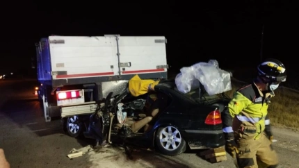 Un bombero interviene en el lugar del accidente, con el turismo empotrado en el camión