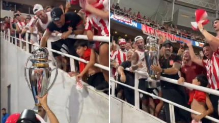 Juan Sebastián Verón levanta la copa de campeón en la grada al estar sancionado.