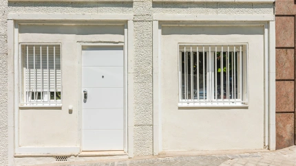 Apartamento tipo loft en planta baja comercial reconvertida con puerta antigua de roble y toldo metálico que marca el acceso a la calle.