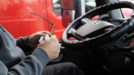 Una persona está dentro de la cabina de un camión sosteniendo vasos y un trozo de papel.