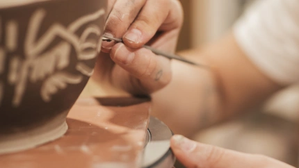 Una artesana decora una pieza de barro moldeada en un torno
